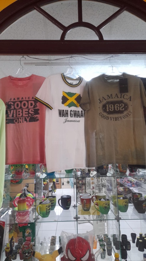 Hanging t-shirts above a glass case of mugs and souvenirs